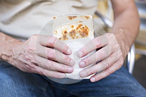 Man holding a wrap, bread, piadina, against white blur background