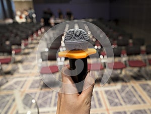Man holding yellow black microphone at large conference hall