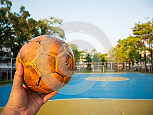 A man holding a yellow soccer ball on a blue football field