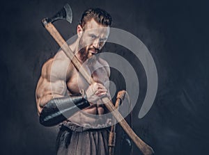 A man holds axe over dark grey background.