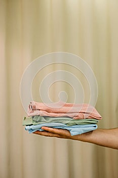 A man holds baby things on a beige background. Background for children`s clothing store