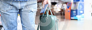 Man holds bag with a passport and tickets in his hand while standing at airport