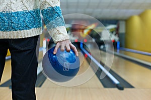 Man holds ball at bowling lane, cropped image