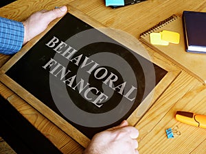 Man holds Behavioral Finance sign on blackboard