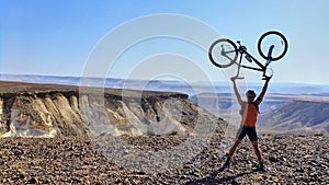 Man holds bicycle on a peak