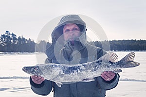 A man holds big pike, winter ice fishing