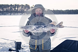A man holds big pike, winter ice fishing