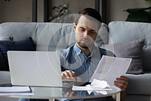 Man holds bills, receipts, using calculator calculates sum to pay