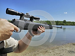 A man holds a black air rifle with a telescopic sight