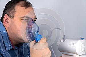 Man holds a breathing mask and inhales. nebulizer and Oxygen Mask. spraying of a drug that is delivered to the patient through a