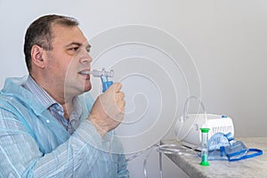 Man holds a breathing tube and inhales. nebulizer and Oxygen Mask. spraying of a drug that is delivered to the patient through a