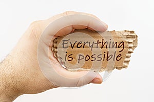 A man holds a cardboard in his hand on which it is written - Everything is possible