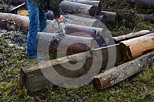 man holds chainsaw and saws log. Chain saw is in motion, sawdust is flying apart. Equipment for gardeners and loggers.