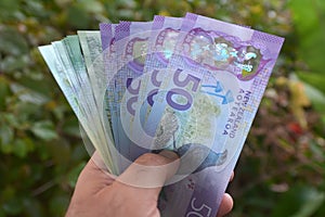 Man holds Cook Islands dollar and New Zealand banknotes