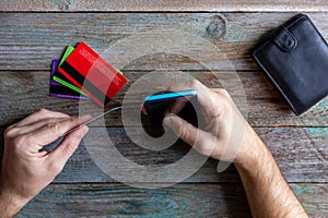 A man holds a credit card and uses a mobile phone top view, payment for purchases in online stores