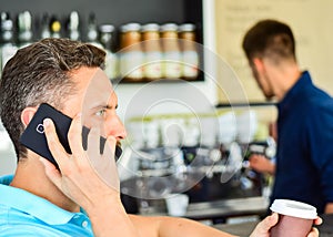 Man holds cup of drink while have mobile conversation. Coffee to go useful option for busy people. Call friend to have