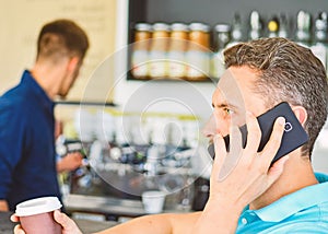 Man holds cup of drink while have mobile conversation. Coffee to go useful option for busy people. Call friend to have