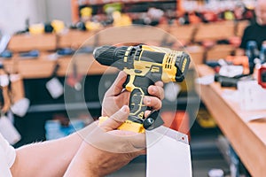 A man holds a drill for drilling in his hands. Concept man selects a product in a hardware store