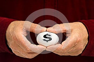 Man holds egg with dollar sign ($) written on it