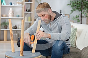 Man holds electric drill and repairs chair