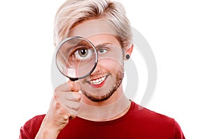 Man holds on eye magnifying glass looking through loupe