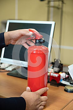 man holds a fire extinguisher in his hands against the background of office equipment.
