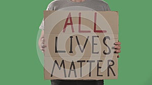 Man holds in front of him a poster from a cardboard box with the words ALL LIVES MATTER. Concept of strike and anti
