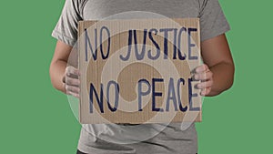Man holds in front of him a poster from a cardboard box with the words NO JUSTICE NO PEACE. Concept of strike and anti