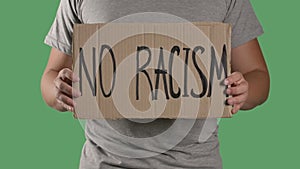 Man holds in front of him a poster from a cardboard box with the words NO RACISM. Concept of strike and anti racism