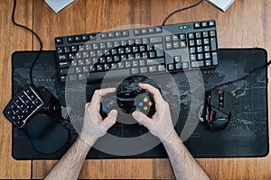 a man holds a game pad around a gaming keyboard in his hands, a game pad mouse. top view