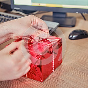 A man holds a gift on his office desk at Christmas and New Year Eve. Surprises and gifts for the holidays