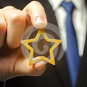 Man holds a golden star in his hand. Symbol of success and excellence. Good reputation, prestige, high recognition. Status, rating