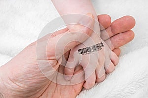 Man holds hand of a baby with bar code on it. Genetic cloning concept photo