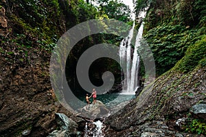 A man holds the hand of a beautiful woman at a waterfall. A couple in love on a waterfall. Honeymoon trip. Happy couple