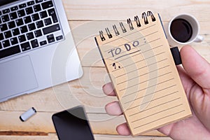 Man holds in hand a notepad. notebook, phone, cup of coffee near