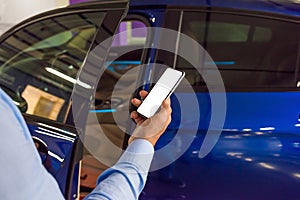 A man holds in a hand a telephone, smart phone on a background of car