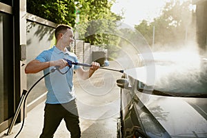 Man holds high pressure water gun, auto wash