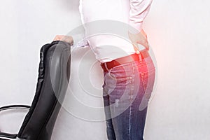 A man holds his back holding an office chair concept of back pain, pinched nerve and myofascial syndrome, inflammation, lumbago photo