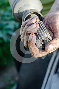A man holds in his hand a driveshaft of a car.