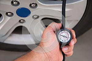 Man holds in his hand manometer of automobile electric compressor, inflating  tire, repaired after puncture. Checking pressure