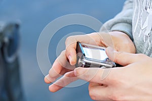 Man holds in his hands and looks through footage on an action camera