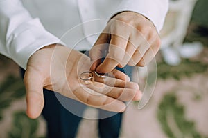 A man holds in his hands on the palms of the wedding gold rings. Close-up