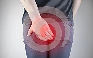 A man holds his hands to the ass feeling pain. Conversion of pain in the rectum, hemorrhoids and pain in the excretory system of