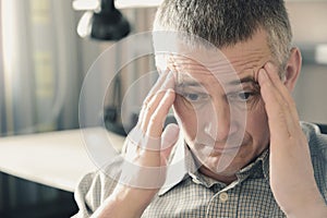 The man holds his head in his hands. . Problems in personal life and at work. Stress. Migraine is a consequence of stress