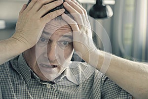 The man holds his head in his hands. . Problems in personal life and at work. Stress. Migraine is a consequence of stress