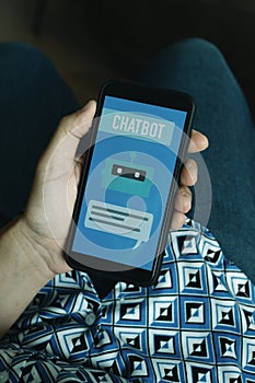man holds his smartphone with the text chatbot