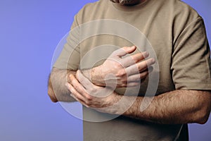 A man holds his wrist in pain. The hand tightly clasps the affected area, emphasizing the soreness and need for support photo