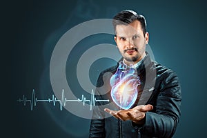 A man holds a hologram of a heart on his hand. The concept of heart transplantation, heart disease, stroke, medicine