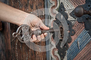 Man holds huge key in hand and unlocks large door