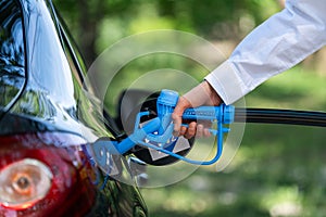 Man holds a hydrogen fueling nozzle. Refueling car with hydrogen fuel. Concept.